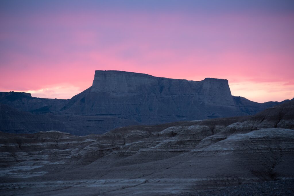 Pista de grava desértica con montañas al fondo durante el atardecer en la ruta de bikepacking del Guardián Solitario.