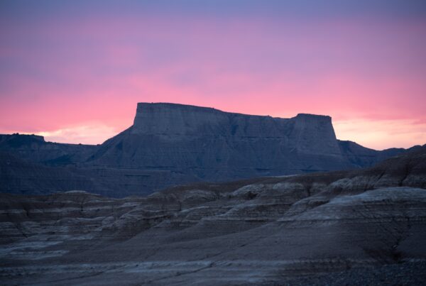 Pista de grava desértica con montañas al fondo durante el atardecer en la ruta de bikepacking del Guardián Solitario.