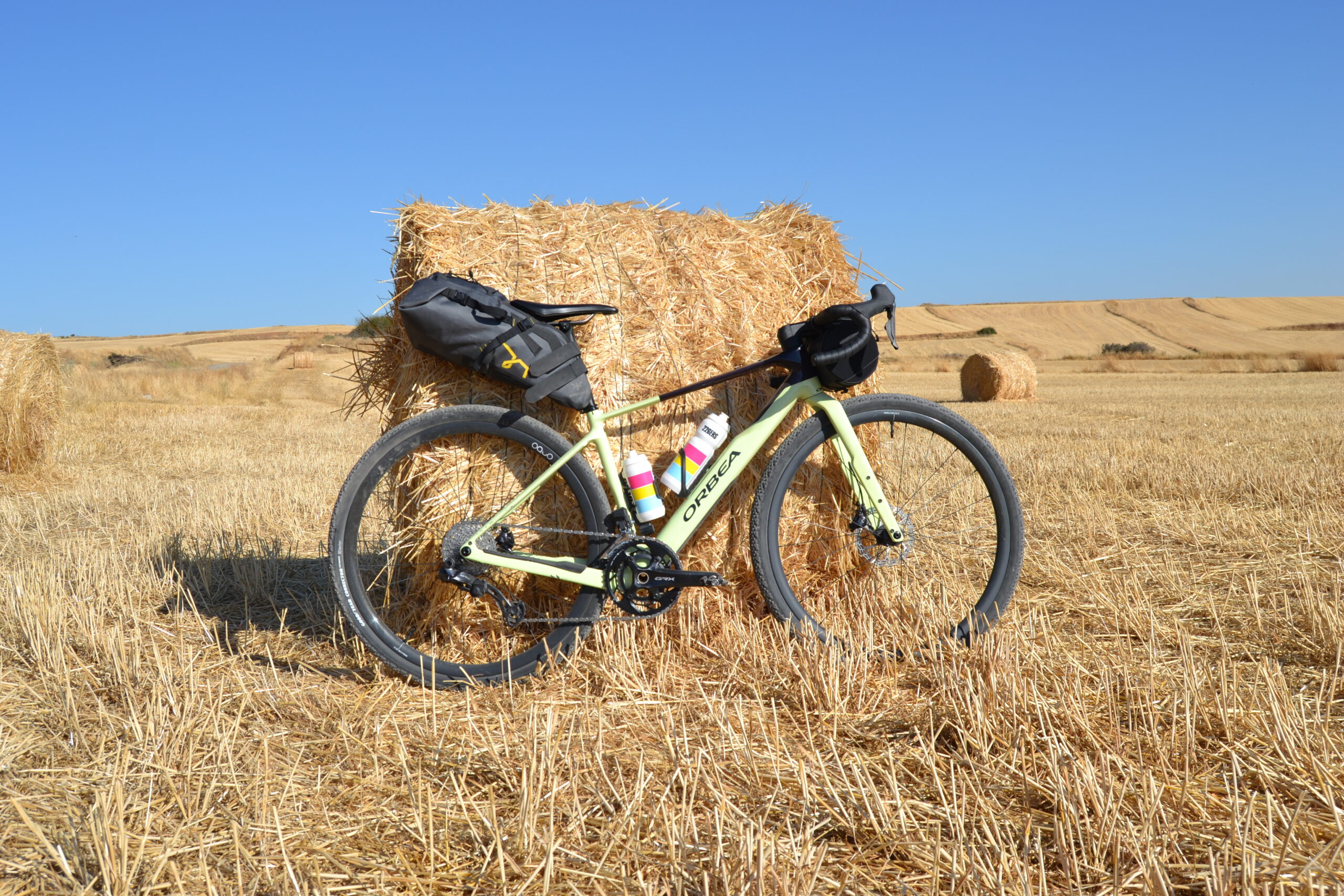 Bicicleta de gravel cargada con alforjas de bikepacking apoyada en una bala de paja