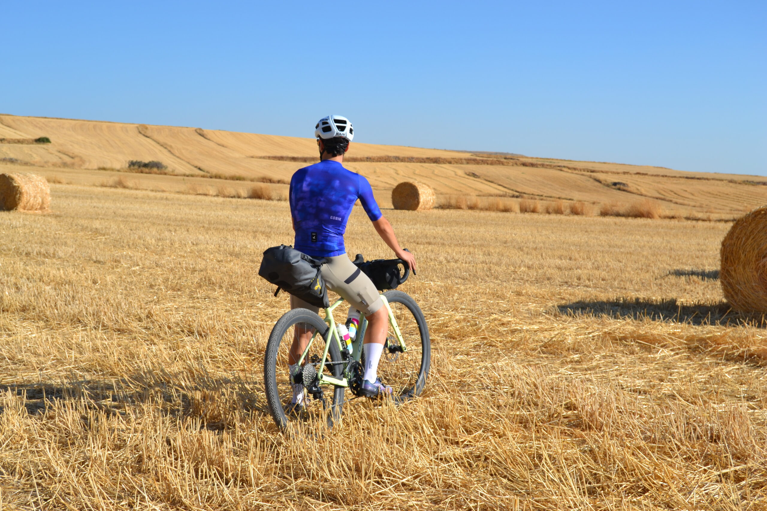 Ciclista detenido entre campos de rastrojo bajo el Moncayo